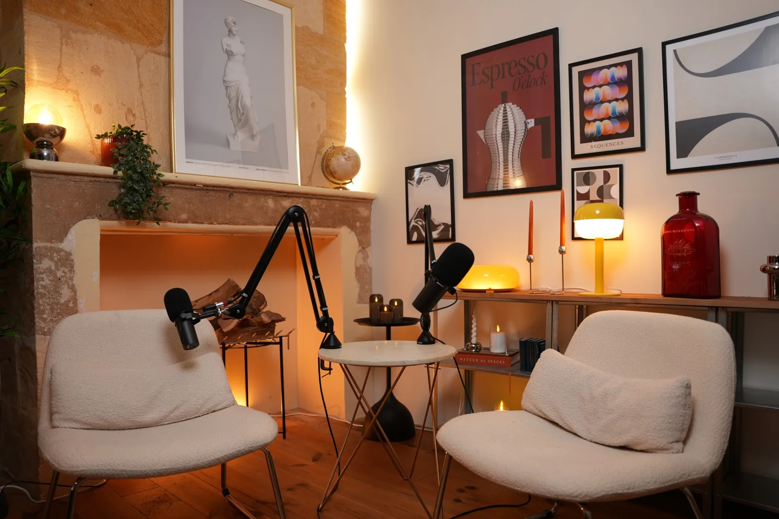 Décor Pluton du studio podcast KOSMOS à Bordeaux : cheminée en pierre, affiches et fauteuils blancs
