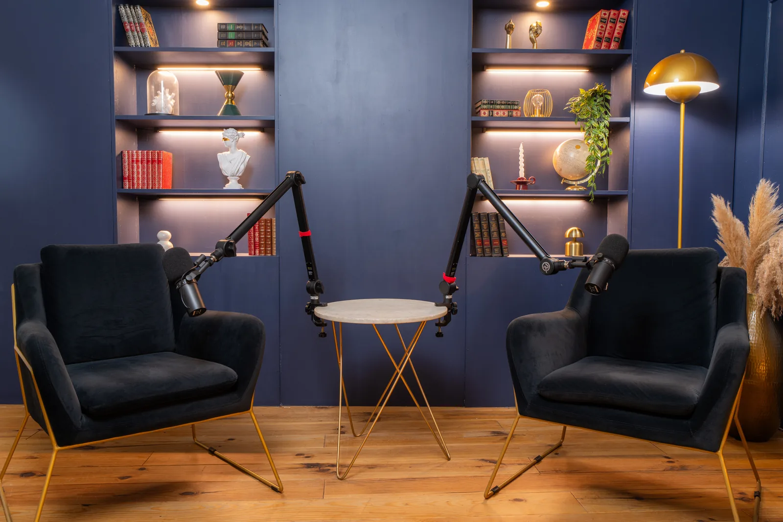 Décor Vénus du studio podcast KOSMOS à Bordeaux : bibliothèque bleu nuit et fauteuils en velours noir