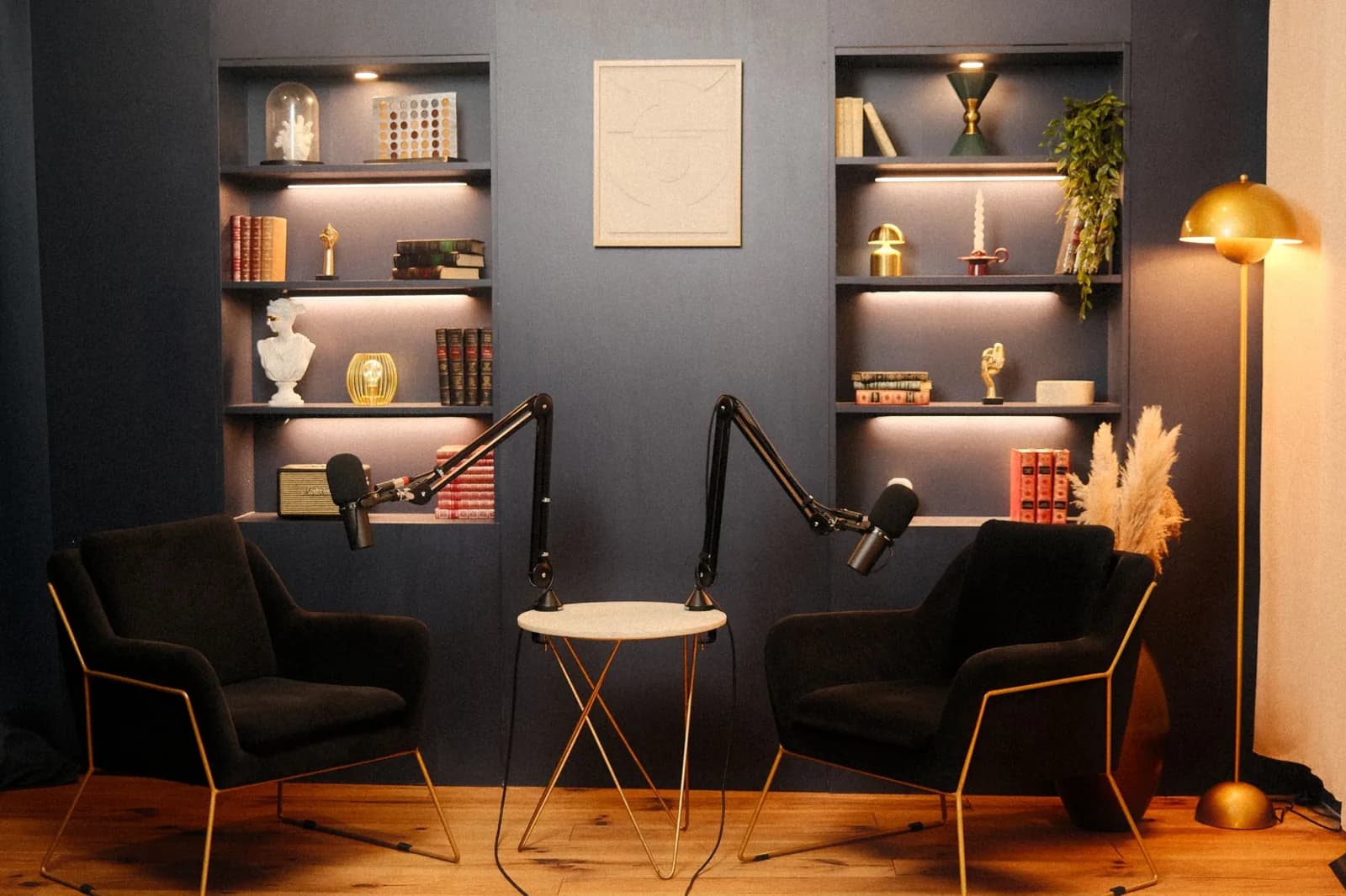 Décor Vénus du studio podcast KOSMOS à Bordeaux : bibliothèque bleu nuit, tableau et fauteuils en velours noir